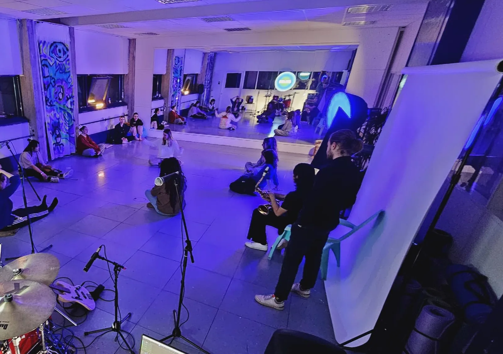 The studio: mirror wall, open floor, painted panels and the AUCH sign, during an evening session.