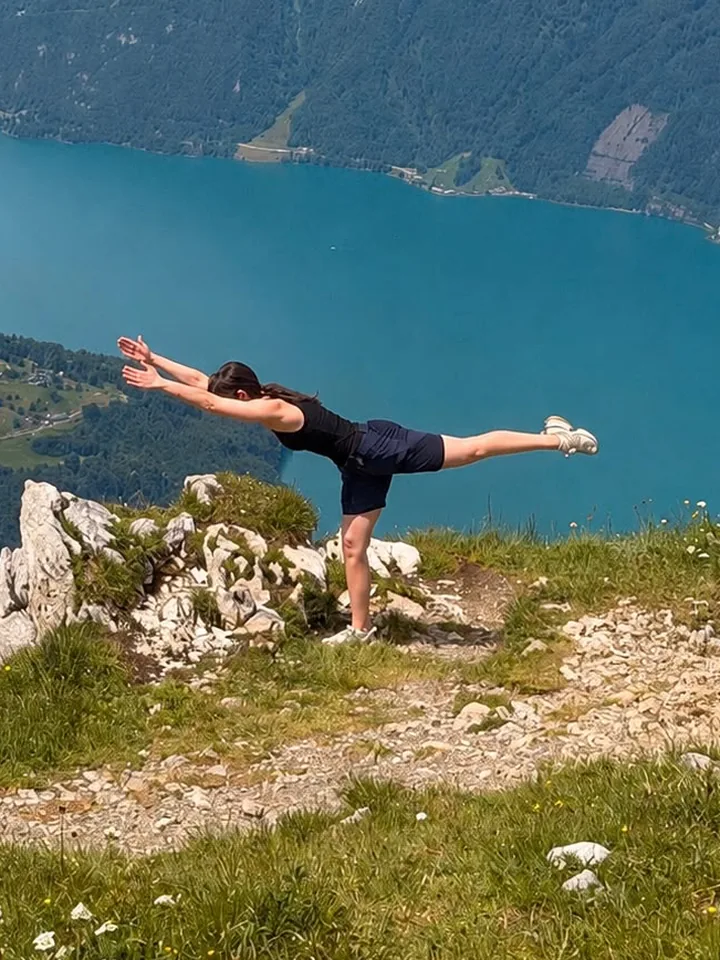 Anhelina Horiuk holding a standing balance on a ridge above a lake.