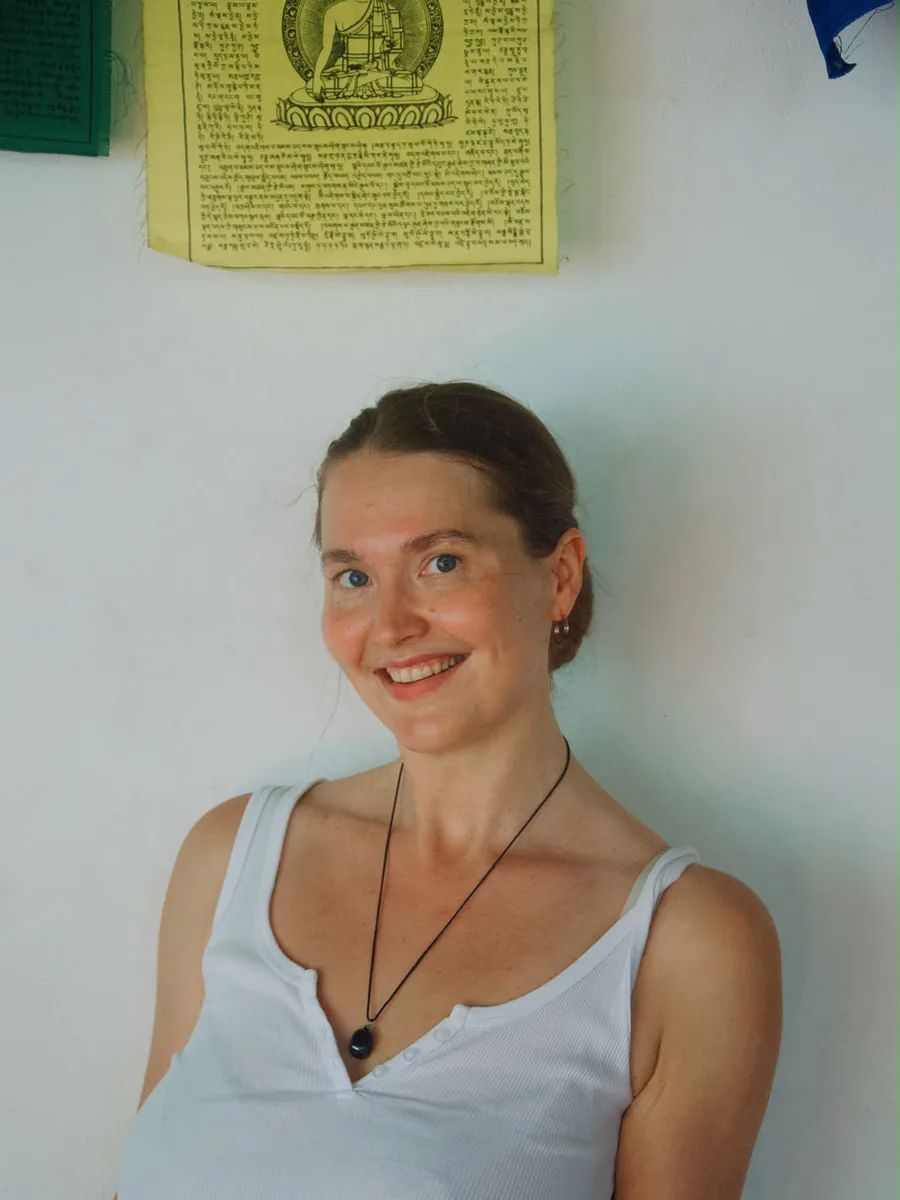 Greta Nadolna smiling in front of a wall of prayer flags.