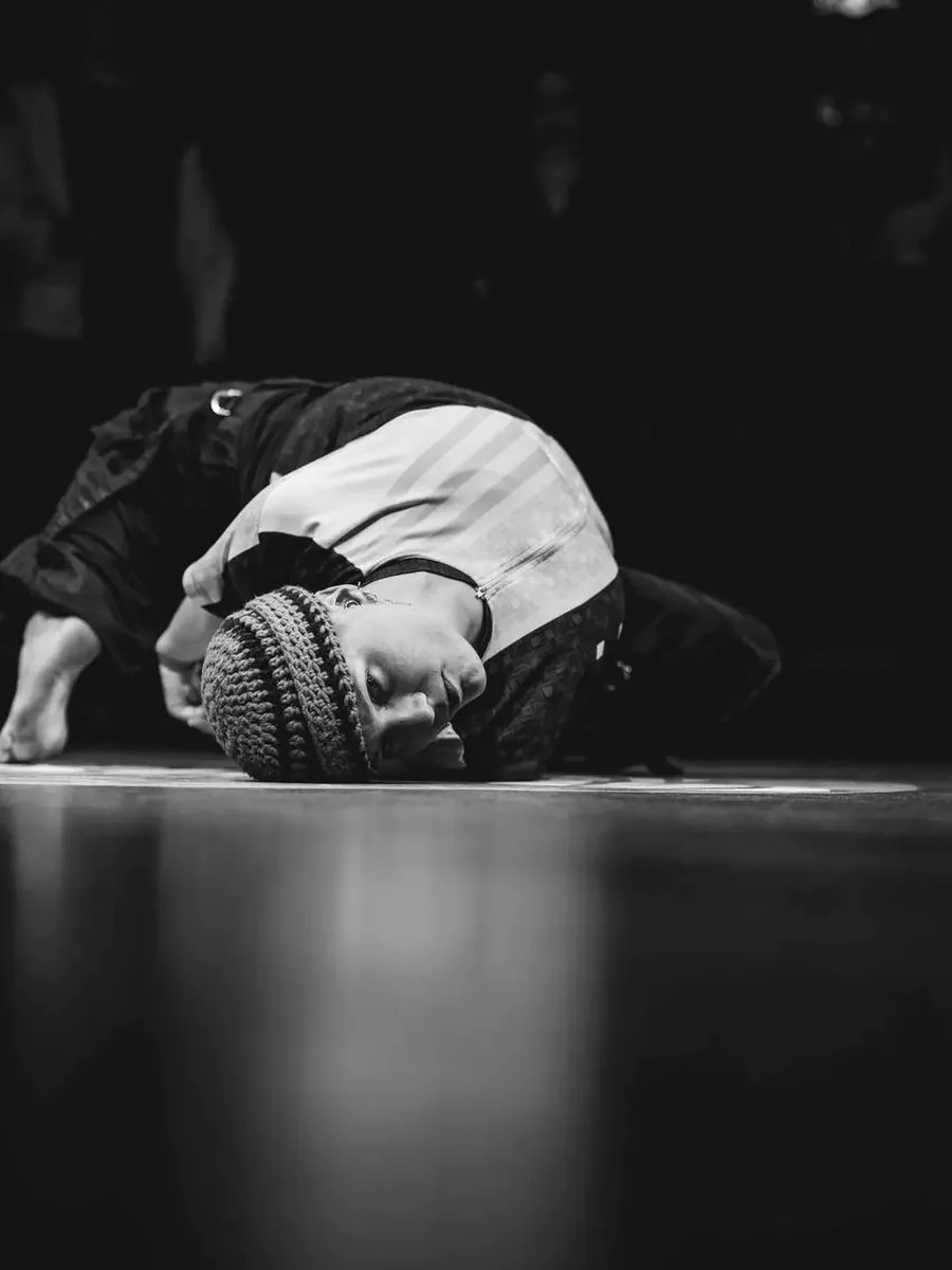 Jana curled on the floor mid-phrase, photographed in black and white.