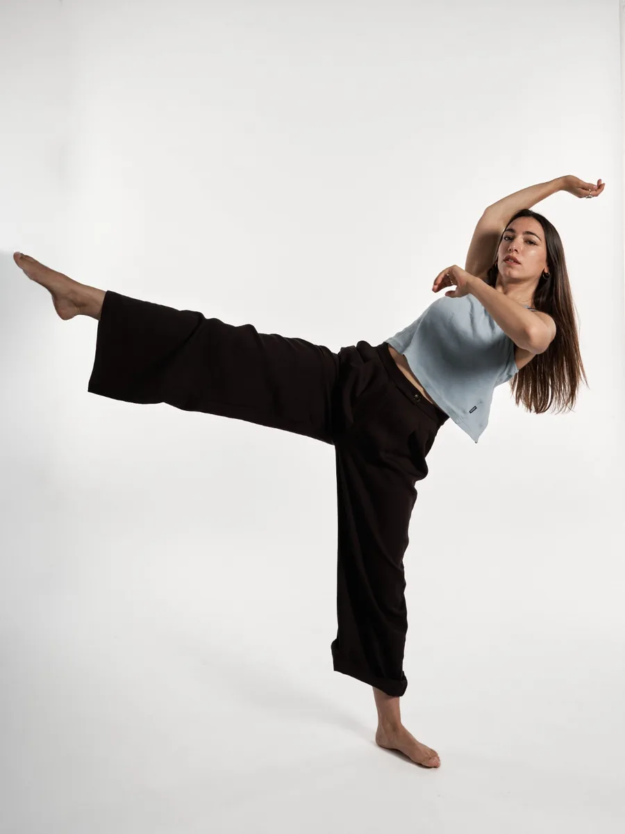 Léa Schneider mid-phrase against a white wall, one leg extended.